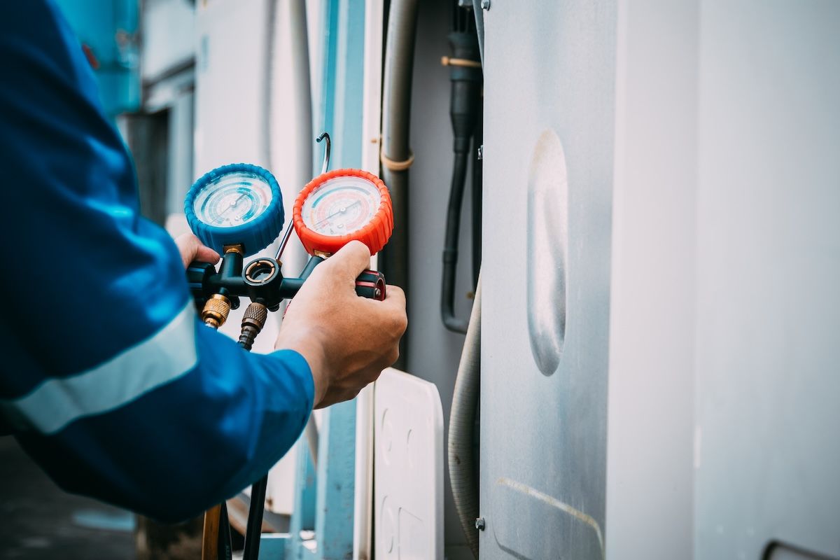 Techniker misst Klimaanlagendruck mit Manometer.